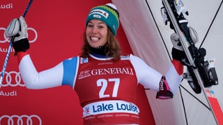 Skiunza che giubilescha e tegna en l'aria bastuns e skis