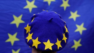 Purtret d'ina chapitscha blaua cun si las stailas da l'UE. 