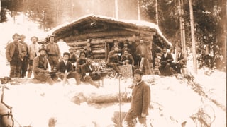 Ina veglia fotografia che mussa lavurers forestals, l'enviern, avant ina tegia da lain.