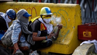 Purtret da trais demonstrants mascrads che sa zuppan davos in bloc da betun. 