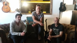 Sandro Dietrich, Lou «Geniuz» Zarra e Stefan «Stämpf» Schmid sesan sin il canapé en lur studio Klangstark a Cuira.