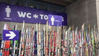 Purtret da skis davant tualetta publica. 