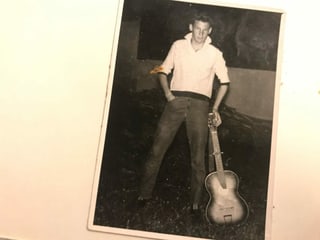 Ina fotografia veglia en alv e nair dad Arturo Casanova, co el stat en pe e tegna dasper el sia ghitarra. El fa endament in zic a James Dean cun il culier da sia chamischa agradsi. 