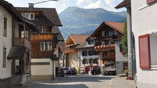 Casas en il center dal vitg da Schiers cun autos parcads davant.