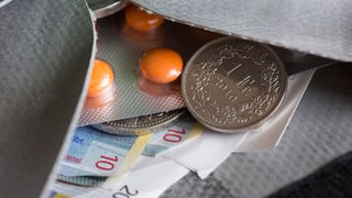 Ina cuverta cun en medicaments, bancnotas e munaida.