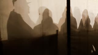 Siluettas da fugitivs che spetgan en ina tenda a Berlin.