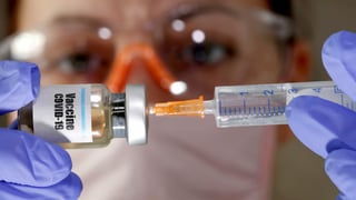 purtret d'in medi u ina media che tegnan ina squitta vid ina buttiglia pitschna, che ha scrit si Vaccin Covid-19.