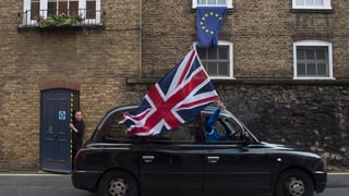 In auto cun ina bandiera da la Gronda Britannia avant ina chasa cun ina bandiera da l'UE. 