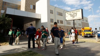 Scolars davant ina scola media en l'America.