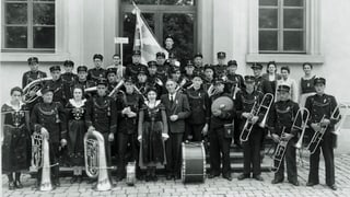 Foto s/w der Musikgesellschaft Tschlin die im freien steht vor einem Haus