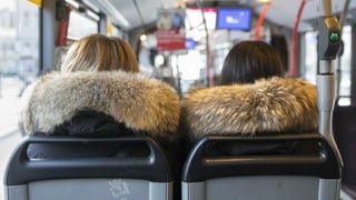 Duas dunnas en in bus portan giaccas cun pail.
