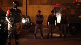 Purtret dad in policist che stat davant in auto cun in'arma. 