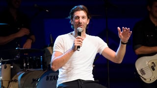 Fabian Cancellara sesa sin ina sutga cun in microfon en maun e discurra cun il public.