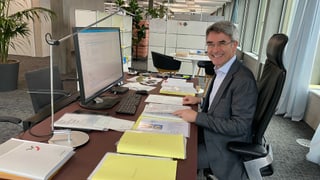 Purtret da Mario Cavigelli davos ses pult en biro Purtret da Mario Cavigelli davos ses pult en biro