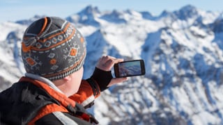 Turist che fa ina fotografia e trametta ella a chasa.
