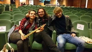 ina dunna e dus umens, tuts trais musicists, sesan en la sala da concert