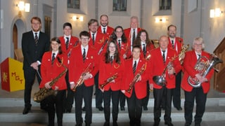 Die Musikgesellschaft Thusis posiert in der Kirche für das Foto, in roter Uniform