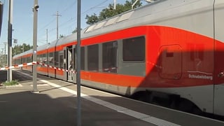 In tren ferma en ina staziun e circumdà cun in bindel da serrada. 