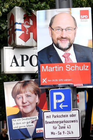 Placats dad Angela Merkel e Martin Schulz vid in pitga cun tavla da parcar ed inscripziuns.