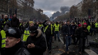 Purtret dals «Gilets jaunes» che van per las vias. 