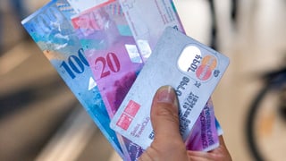 in maun che tegn duas bancnotas ed ina carta da credit