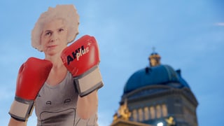 Ina figura da chartun ch'era plazzada sin la Plazza federala il december 2015. La figura mussa ina tatta cun guants da box cotschens cun si AHV plus.