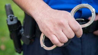 Purtret d'in polizist che tign en maun pastuiras. 