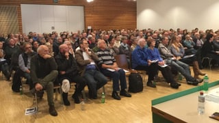 Ina fulla da persunas che sesan davant in pult ch'in discurra. 