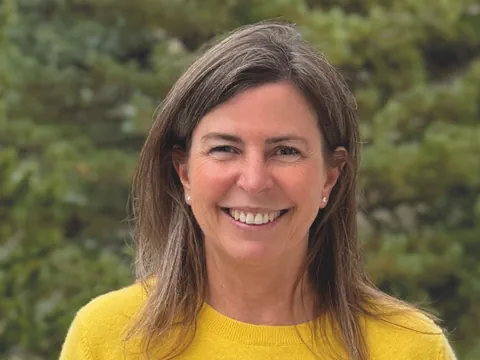 Frau mit gelbem Pullover lächelt im Freien.