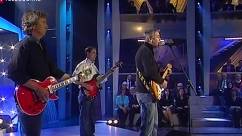 Drei Musiker spielen Gitarren auf einer Bühne in einer Show.