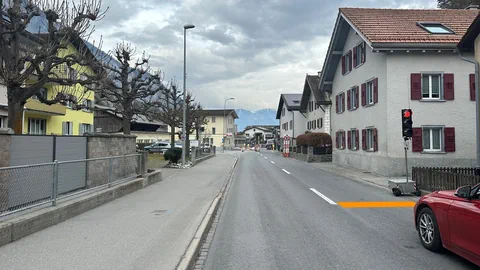 Leere Strasse in Wohngebiet mit Bergen im Hintergrund.