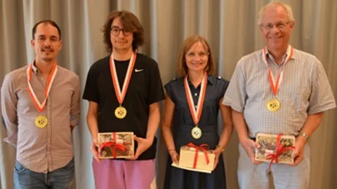 Vier Personen mit Medaillen und Geschenken.