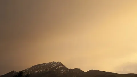 Berglandschaft bei Sonnenuntergang mit wolkenbedecktem Himmel.