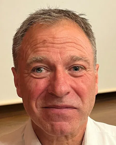 Ein älterer Mann mit grauem Haar lächelt.