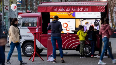 Menschen vor einem rot-weissen Infostandbus.