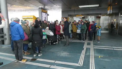 Gruppe von Menschen versammelt am Bahnhof.