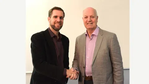 Zwei Männer schütteln Hände und lächeln.