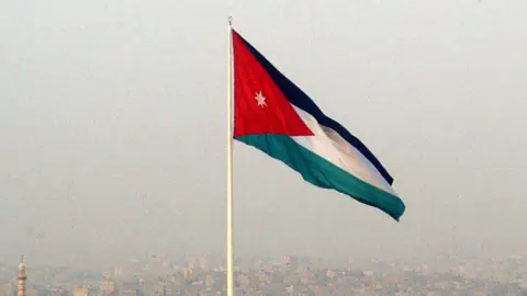 Grosse Flagge weht im Wind über einer verschwommenen Stadtlandschaft.