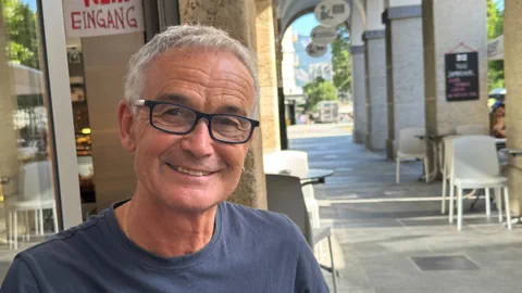 Älterer Mann mit Brille in einem Strassencafé.