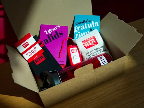 Geschenkbox mit Büchern, Socken und einem Beutel auf einem Holztisch.