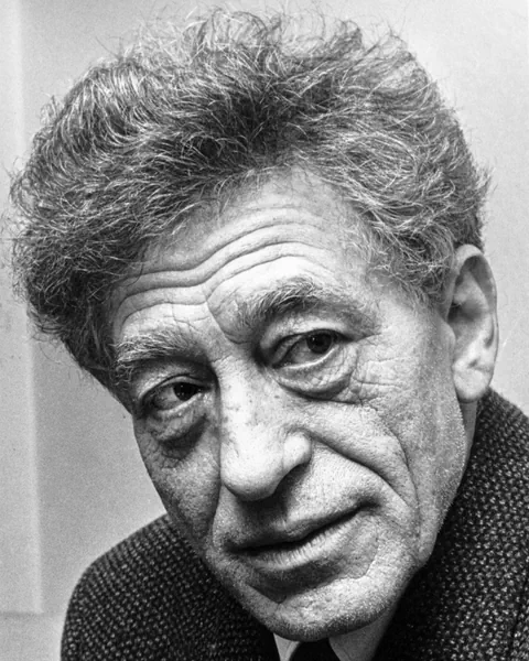 Schwarzweissporträt eines älteren Mannes mit lockigem Haar.