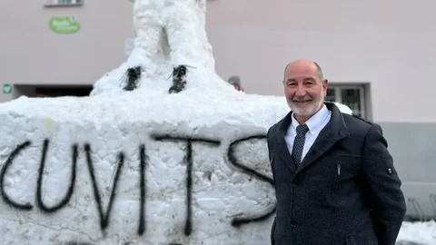 Mann steht vor Schneeskulptur mit Graffiti.