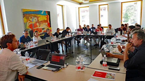 Menschen in einem Konferenzraum mit Laptops und Wasserflaschen.