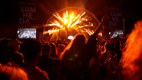 Menschenmenge bei einem Konzert mit beleuchteter Bühne.