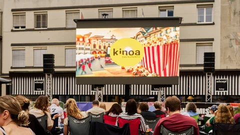 Kulturkino Kinoa auf dem Kornplatz in Chur – diees Jahr mit einem rätoromanischen Themenabend. Publikum mit Leinwand.