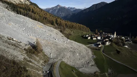 Felsrutsch neben Dorf in alpiner Landschaft.