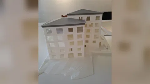 Modell von zwei modernen Gebäuden mit schrägen Dächern auf hellem Untergrund.