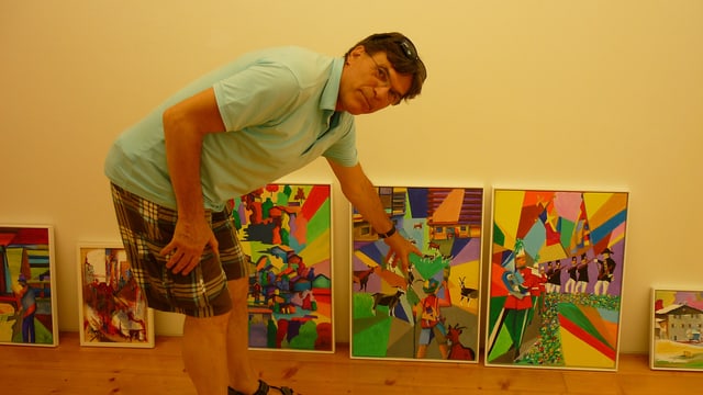 Il pictur-artist Lucas Tomaschett avant che pender si ses maletgs en il Museum Sursilvan Cuort Ligia Grischa