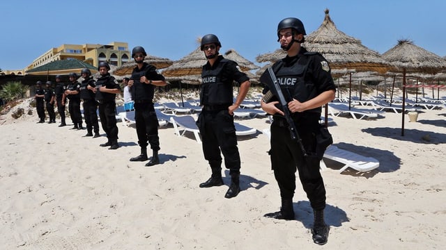 Policits che stattan guardia tar ina riva a Sousse.