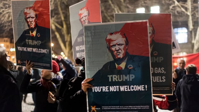 Persunas cun placats cunter Trump cun l'inscripziun: "Trump you're not welcome!